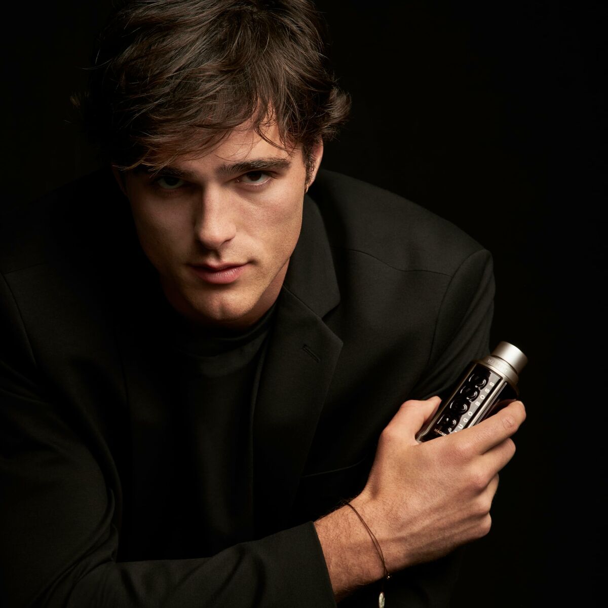 Homme élégant tenant le parfum unisexe Hugo Boss-boss THE SCENT 100 ml, avec un regard captivant.