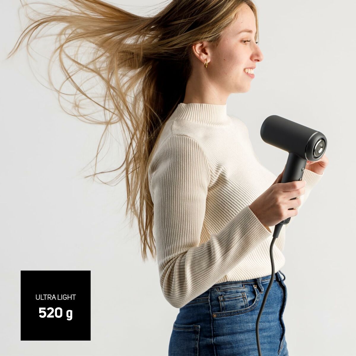 Femme utilisant un sèche-cheveux ultra léger de 520 g, témoignant de sa puissance et praticité.